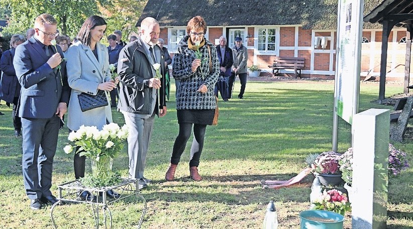 Jarek und Iwona Fabisiak (von links), Brian Gerken und Regina Bastein legen Blumen vor dem Grabstein nieder.